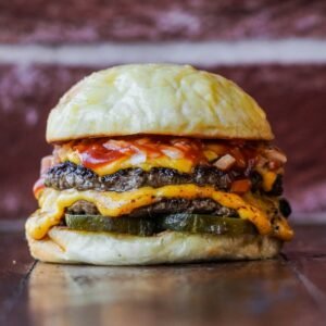 a cheeseburger on a bun with a pickle on the side