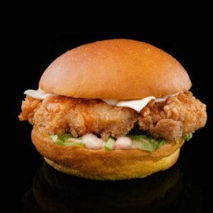 a chicken sandwich with lettuce and mayonnaise on a black background